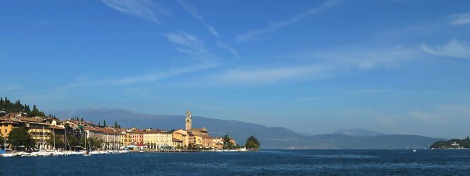 Trip Niederlande beliebte Urlaubsziele am Gardasee -  Mit einer Fläche von 370 km² ist der Gardasee der größte See Italiens. Es liegt am Fuße der Alpen und erstreckt sich über drei Staaten: Lombardei, Venetien und Trentino. Die maximale Tiefe des Sees beträgt 346 m, er hat eine längliche Form und sein nördliches Ende ist sehr schmal. Dort ist der See von den Bergen der Gruppo di Baldo umgeben. Du trittst aus deinem gemütlichen Hotelzimmer und es begrüßt dich die warme italienische Sonne. Du blickst auf den atemberaubenden Gardasee, der in zahlreichen Blautönen schimmert - von tiefem Dunkelblau bis zu funkelndem Türkis. Majestätische Berge umgeben dich, während die Brise sanft deine Haut streichelt und der Duft von blühenden Zitronenbäumen deine Nase kitzelt. Du schlenderst die malerischen, engen Gassen entlang, vorbei an farbenfrohen, blumengeschmückten Häusern. Vereinzelt unterbricht das fröhliche Lachen der Einheimischen die friedvolle Stille. Du fühlst dich wie in einem Traum, der nicht enden will. Jeder Schritt führt dich zu neuen Entdeckungen und Abenteuern. Du probierst die köstliche italienische Küche mit ihren frischen Zutaten und verführerischen Aromen. Die Sonne geht langsam unter und taucht den Himmel in ein leuchtendes Orange-rot - ein spektakulärer Anblick.